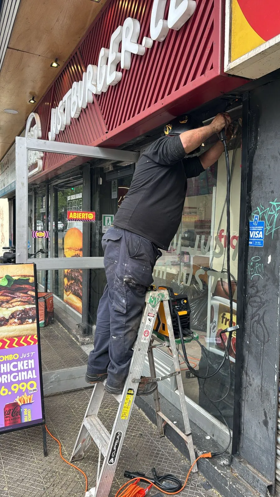 Técnico INGEGAR instalando cortina metálica en local Just Burger, Santiago