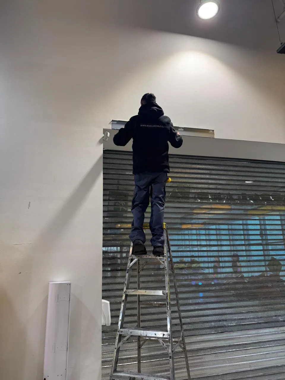 Técnico INGEGAR ajustando cortina metálica de local comercial en Santiago