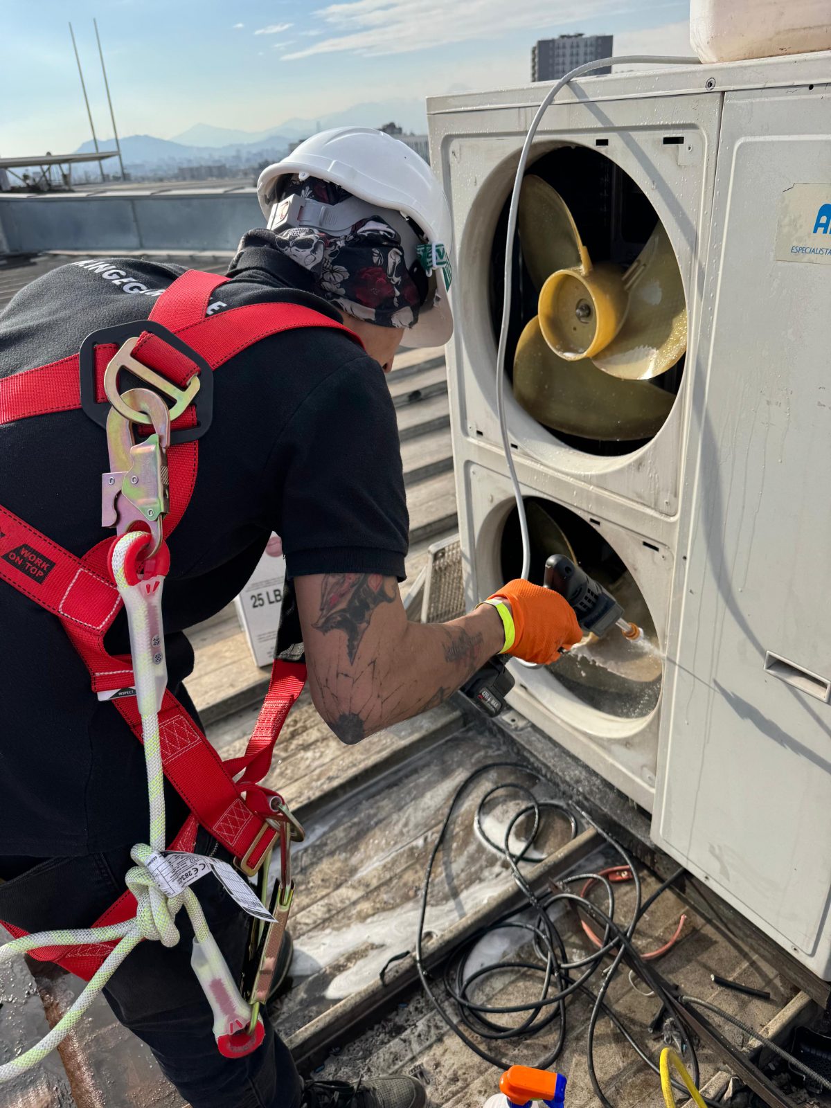 Técnico INGEGAR con arnés y EPP en mantención de condensador HVAC en azotea