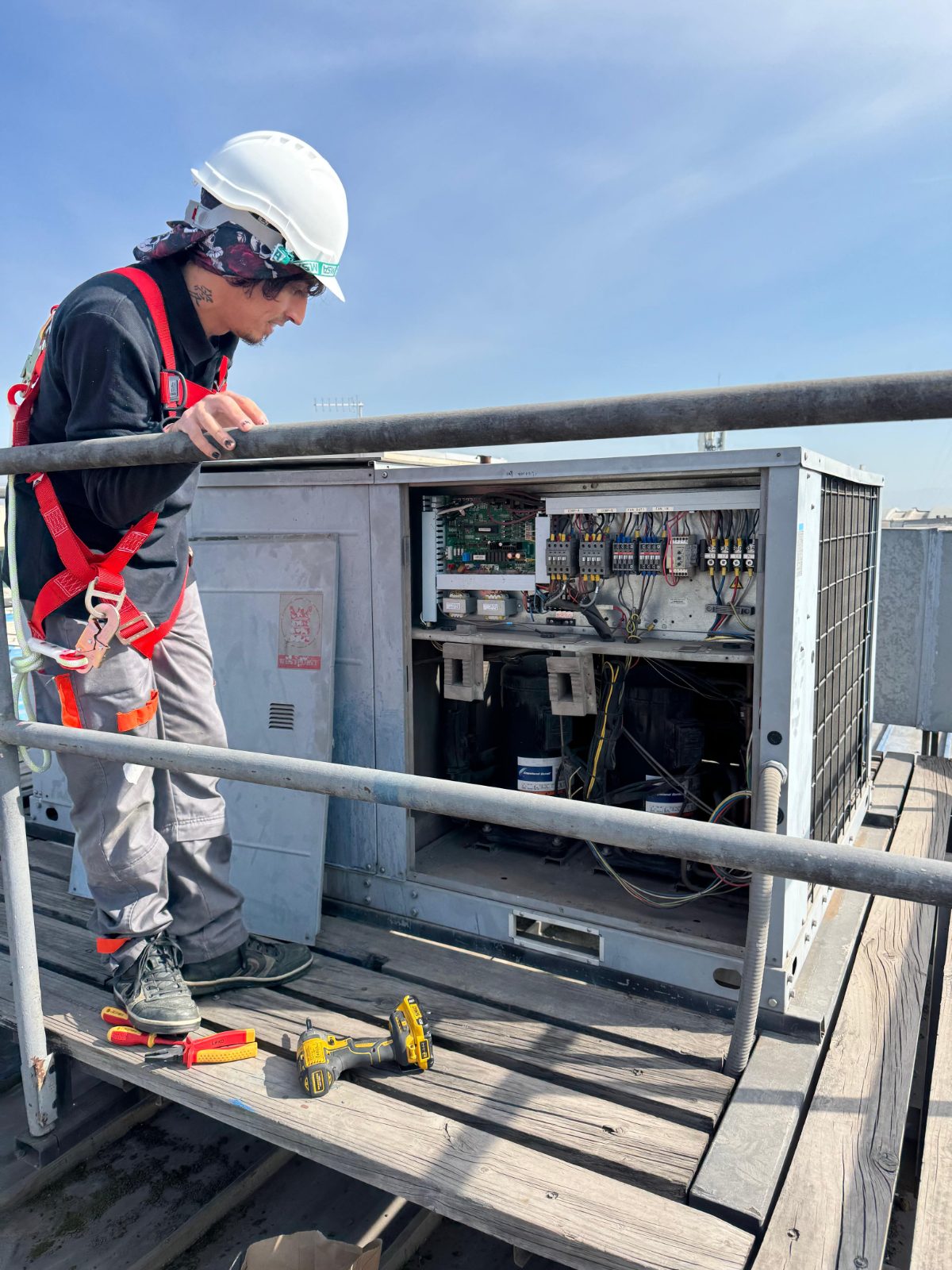 Técnico INGEGAR con arnés revisando tablero de equipo HVAC en azotea, Santiago